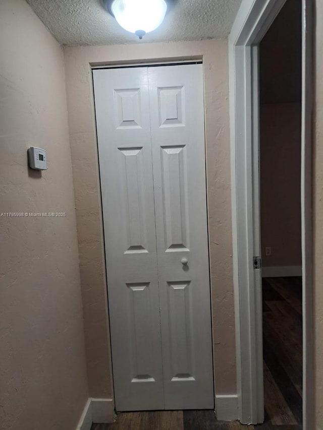room details with baseboards, a textured ceiling, a textured wall, and wood finished floors