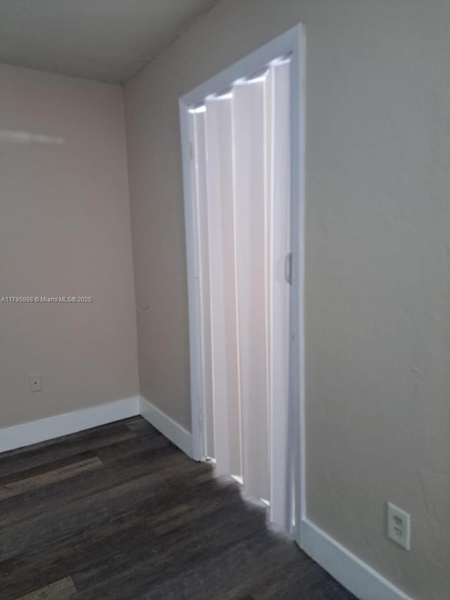 spare room with dark wood-style flooring and baseboards