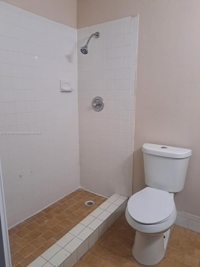bathroom featuring toilet and a tile shower