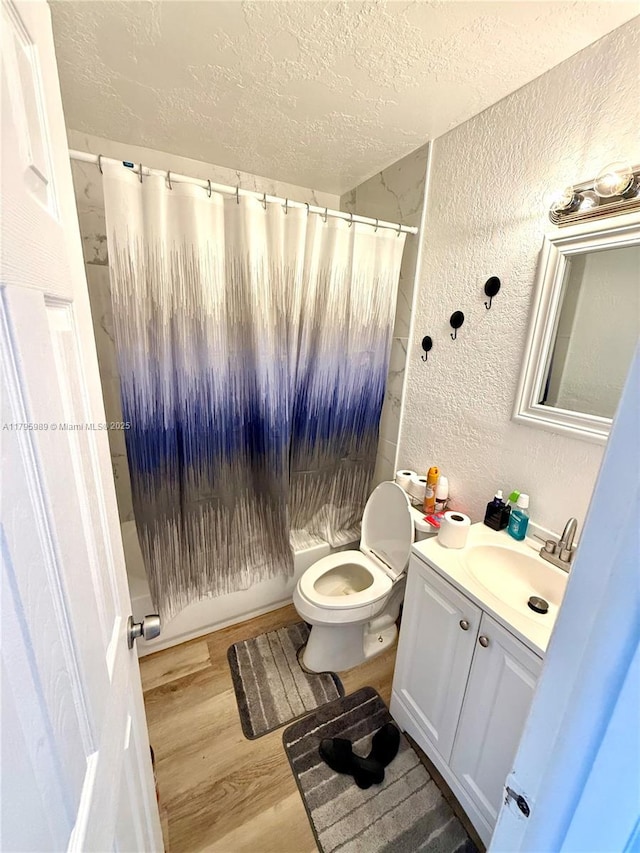 bathroom featuring vanity, a textured wall, wood finished floors, curtained shower, and a textured ceiling