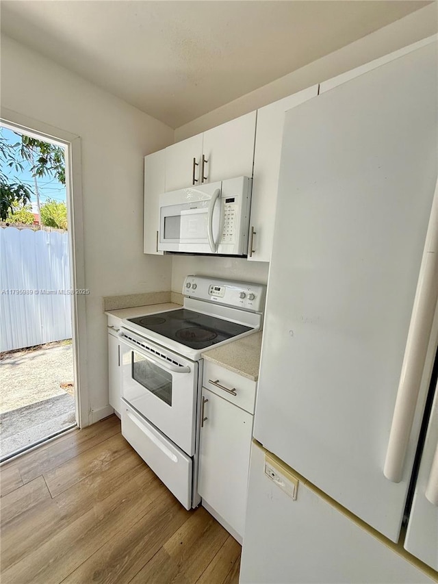 kitchen featuring white appliances, light countertops, white cabinetry, and light wood-style floors