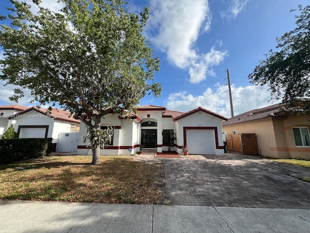 mediterranean / spanish house featuring a garage, a gate, decorative driveway, and a tile roof