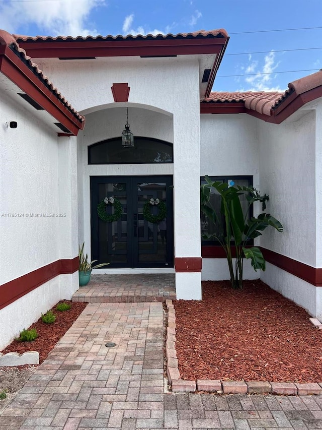 doorway to property with french doors, stucco siding, and a tile roof