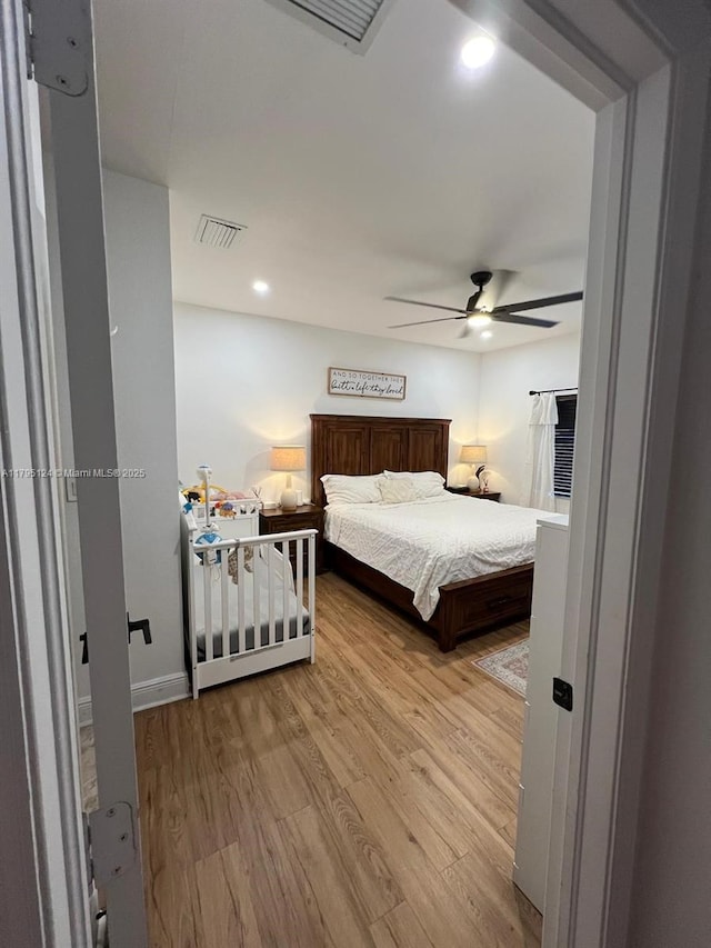 bedroom with ceiling fan, wood finished floors, and visible vents