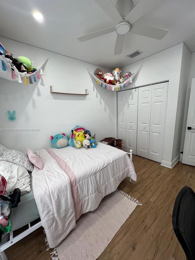 bedroom with ceiling fan, visible vents, wood finished floors, and a closet