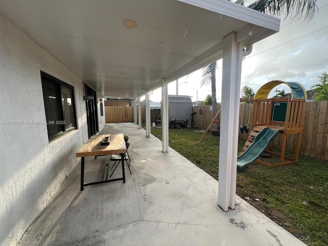 view of patio / terrace featuring a fenced backyard, an outdoor structure, a playground, and a shed
