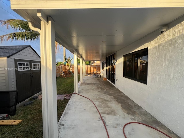 view of patio featuring a storage shed, an outbuilding, a fenced backyard, and a playground