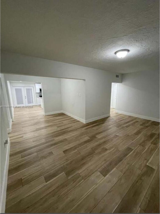spare room featuring baseboards, a textured ceiling, and wood finished floors