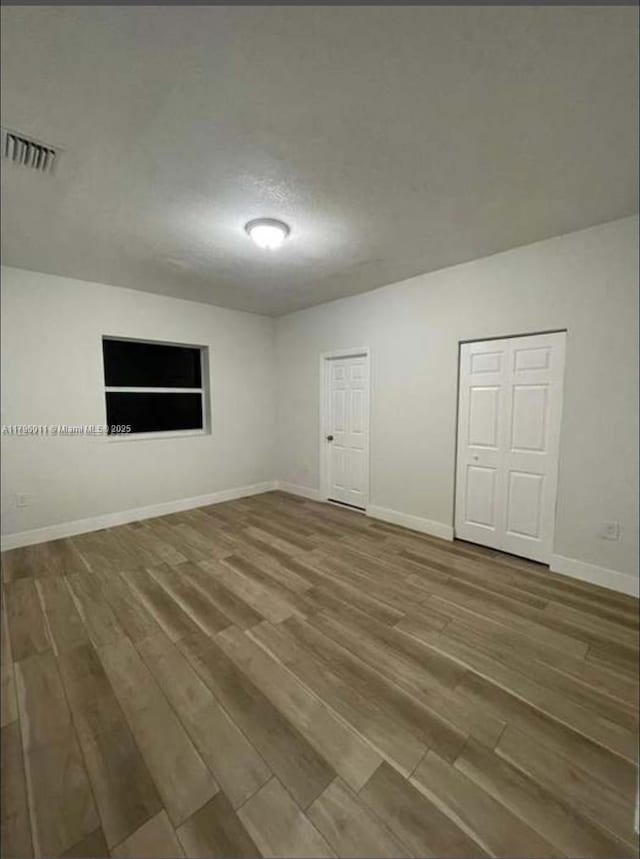 empty room with baseboards, visible vents, and wood finished floors