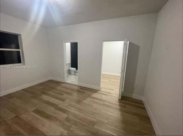 spare room featuring baseboards and wood finished floors