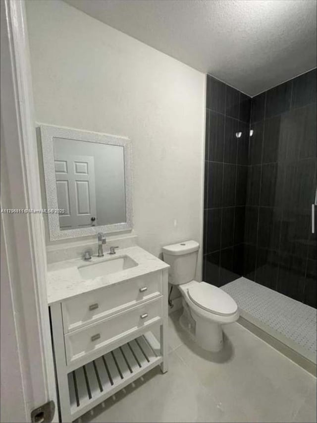 full bath with vanity, toilet, a textured ceiling, tile patterned floors, and a stall shower