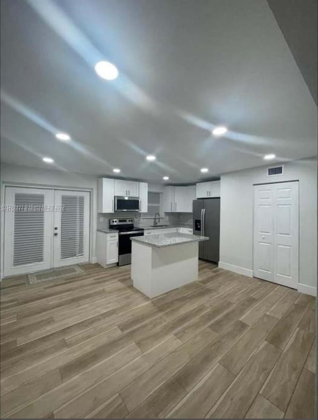 kitchen with appliances with stainless steel finishes, light wood-style floors, white cabinetry, recessed lighting, and visible vents