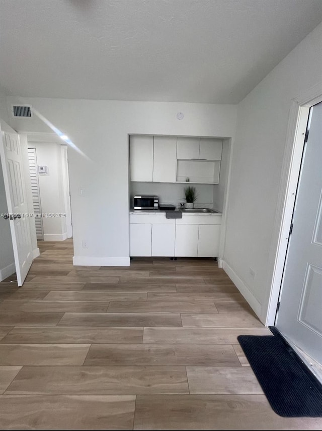 kitchen with visible vents, dark countertops, modern cabinets, baseboards, and light wood finished floors