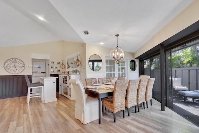 dining space with lofted ceiling, light wood-style floors, and a chandelier
