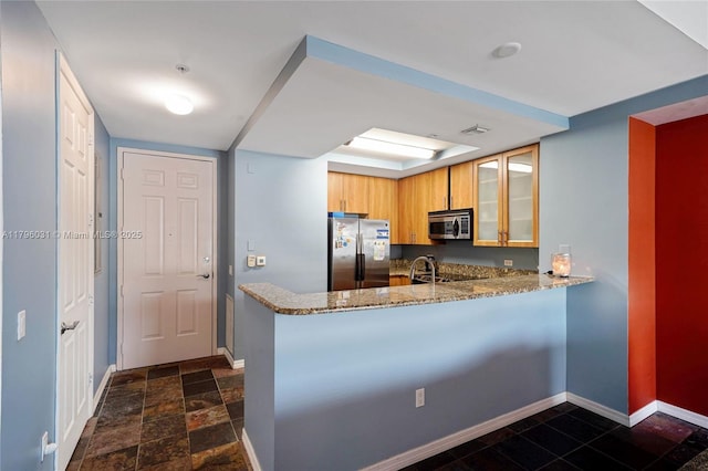 kitchen with baseboards, light stone counters, stainless steel appliances, and glass insert cabinets