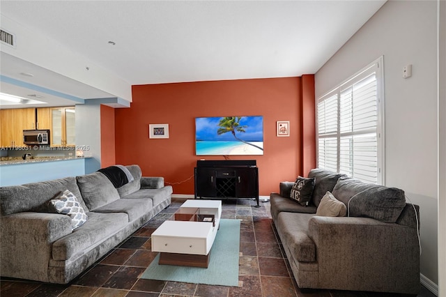 living area featuring baseboards and dark stone finish floors