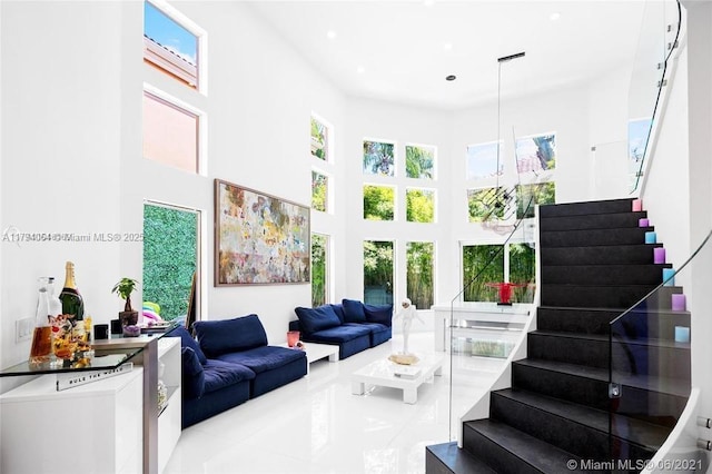 living area with stairs, recessed lighting, tile patterned floors, and a towering ceiling