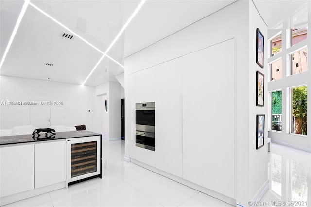 kitchen featuring stainless steel double oven, visible vents, light tile patterned floors, wine cooler, and white cabinetry