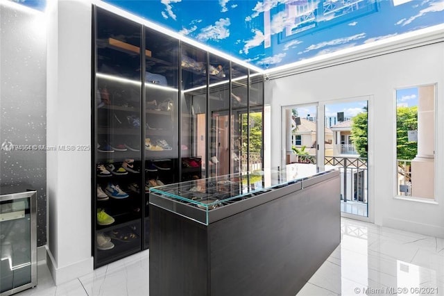 walk in closet featuring beverage cooler and marble finish floor