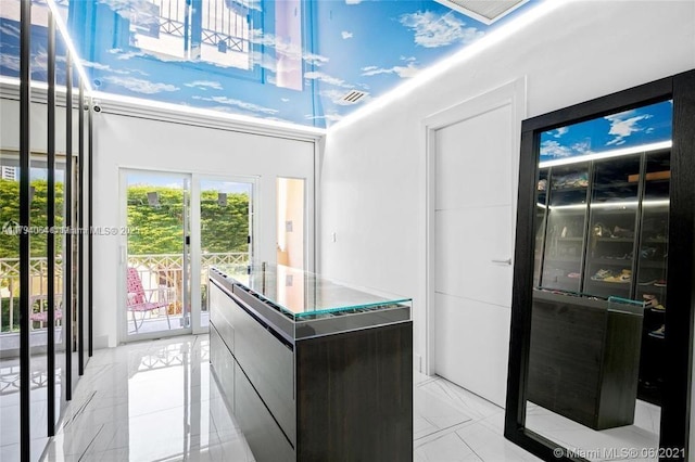 interior space with modern cabinets, visible vents, a kitchen island, and a towering ceiling