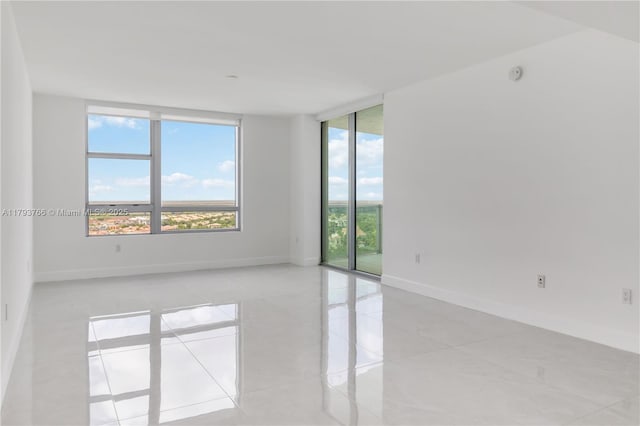 spare room featuring expansive windows, baseboards, and light tile patterned floors