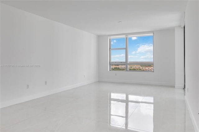 spare room with light tile patterned floors and baseboards