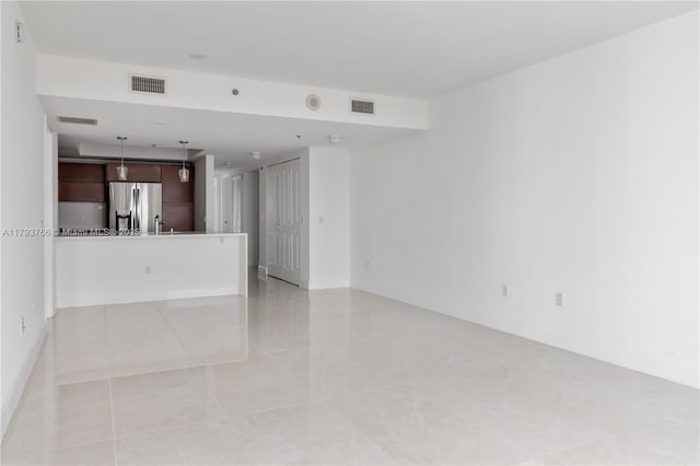 unfurnished living room featuring visible vents and a sink