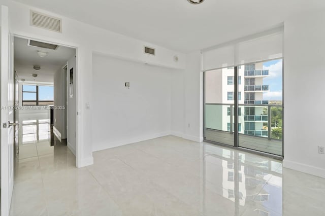 spare room featuring baseboards, light tile patterned floors, and visible vents