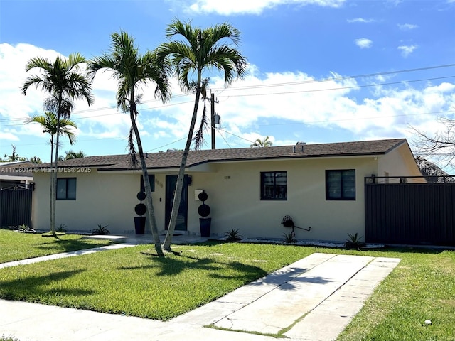 ranch-style house featuring a front lawn, stucco siding, and fence