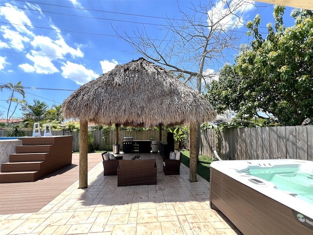 view of patio with a deck, a hot tub, a gazebo, a fenced backyard, and an outdoor hangout area