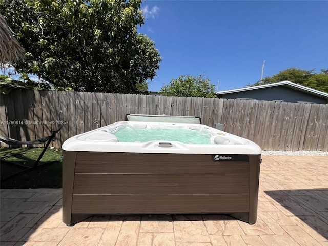 view of patio with a hot tub and fence