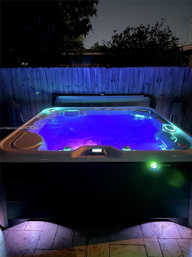 view of pool with a hot tub and fence