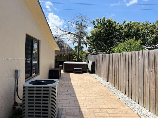 view of patio / terrace with a hot tub, cooling unit, and a fenced backyard
