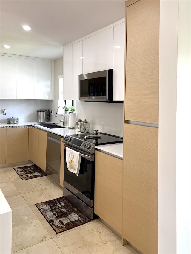 kitchen with modern cabinets, a sink, light countertops, marble finish floor, and stainless steel appliances