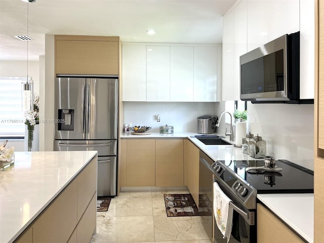 kitchen with light countertops, a sink, appliances with stainless steel finishes, and modern cabinets