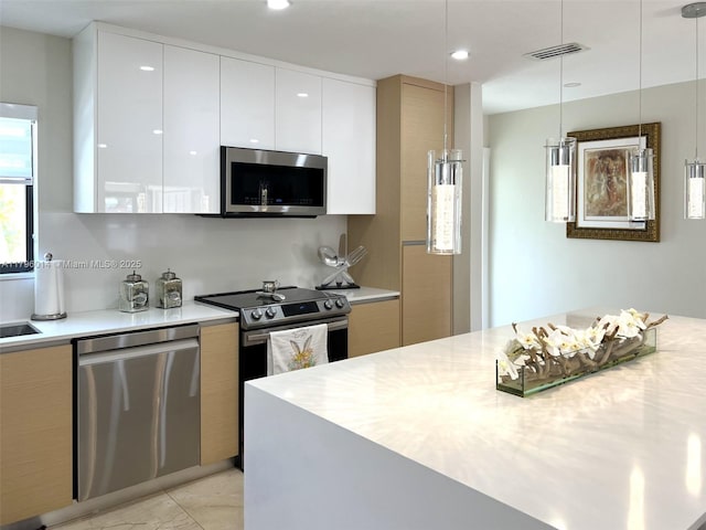 kitchen featuring modern cabinets, light countertops, white cabinets, decorative light fixtures, and stainless steel appliances