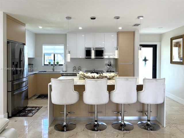 kitchen with a sink, appliances with stainless steel finishes, a breakfast bar, and modern cabinets