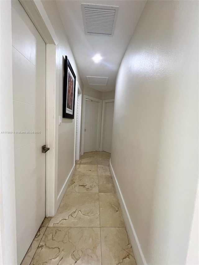 hallway with baseboards, visible vents, and marble finish floor