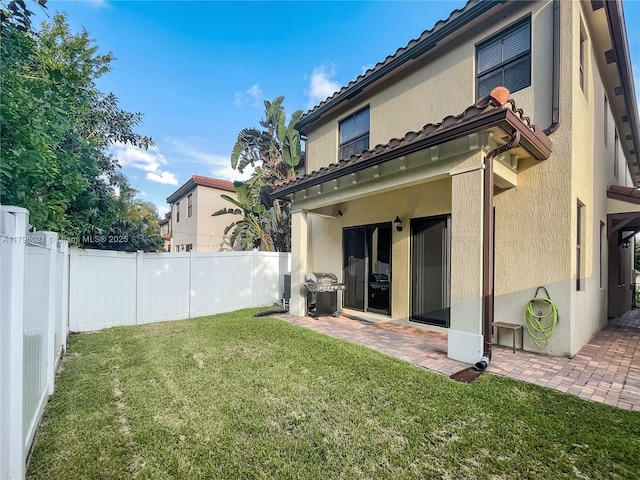 rear view of house featuring a lawn, a patio, a fenced backyard, and stucco siding