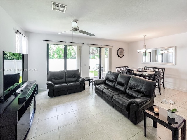 living area with light tile patterned flooring, baseboards, visible vents, and ceiling fan with notable chandelier