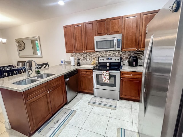 kitchen featuring a peninsula, light tile patterned floors, a sink, appliances with stainless steel finishes, and backsplash