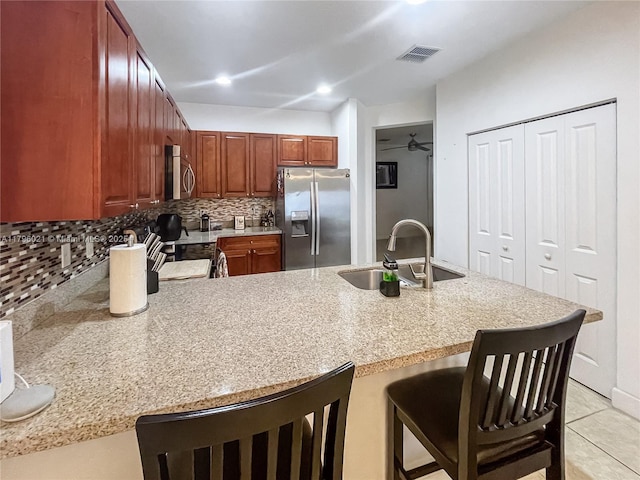 kitchen featuring visible vents, decorative backsplash, a peninsula, a sink, and stainless steel appliances