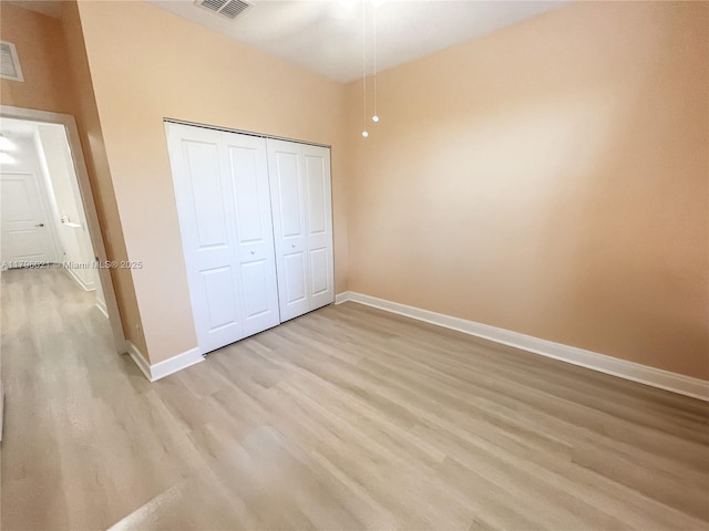 unfurnished bedroom featuring baseboards, a closet, light wood-style flooring, and visible vents