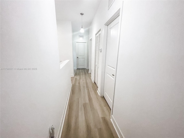 hallway featuring light wood-type flooring and baseboards