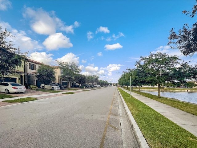 view of street featuring curbs, a water view, and sidewalks