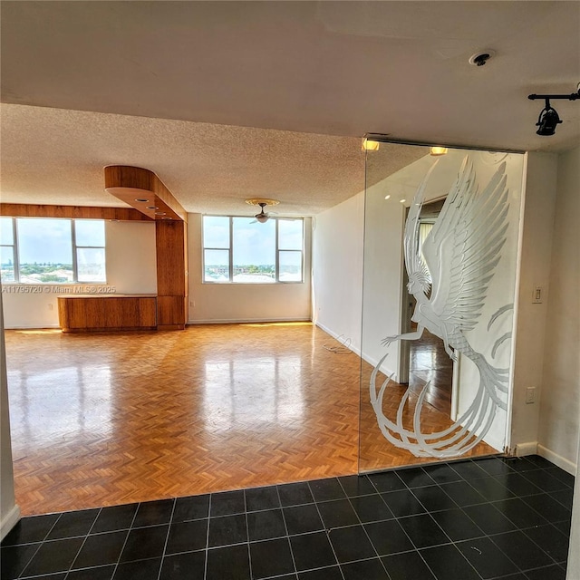 unfurnished living room featuring baseboards, plenty of natural light, and a textured ceiling
