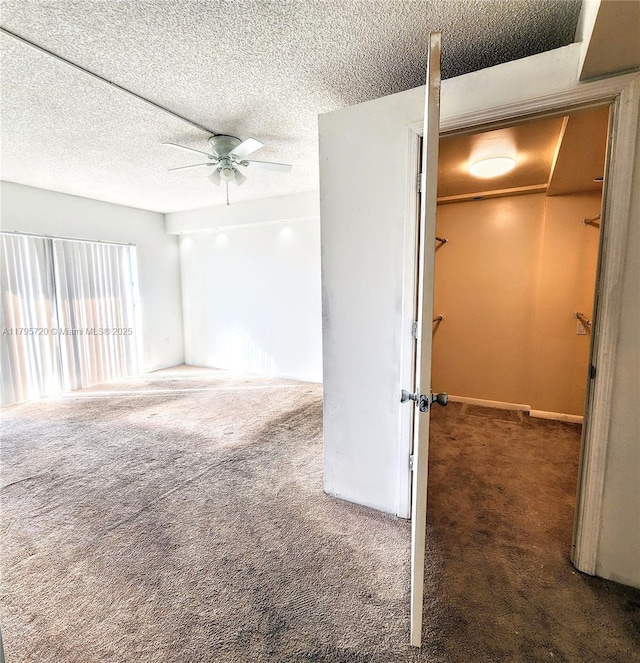 carpeted empty room with baseboards, a ceiling fan, and a textured ceiling