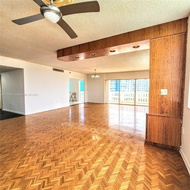 empty room with ceiling fan with notable chandelier, a textured ceiling, and visible vents
