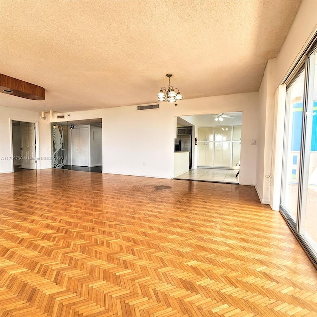 empty room with a textured ceiling, visible vents, and ceiling fan with notable chandelier