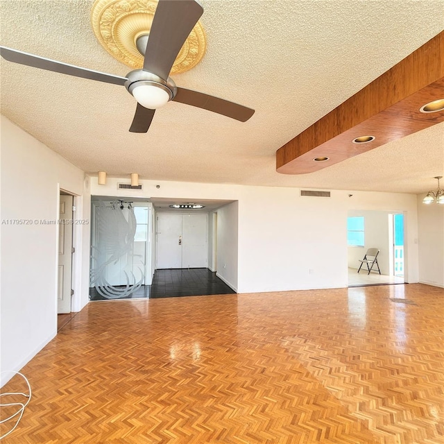 unfurnished room with ceiling fan with notable chandelier, a textured ceiling, and visible vents